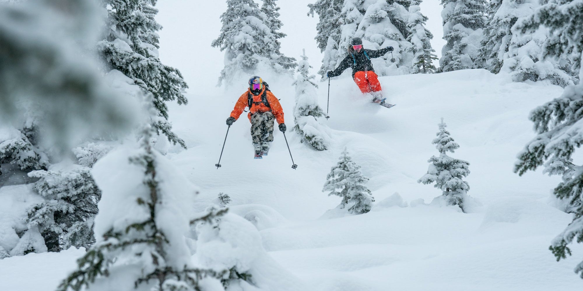 Two skiers powder skiing Atomic skis